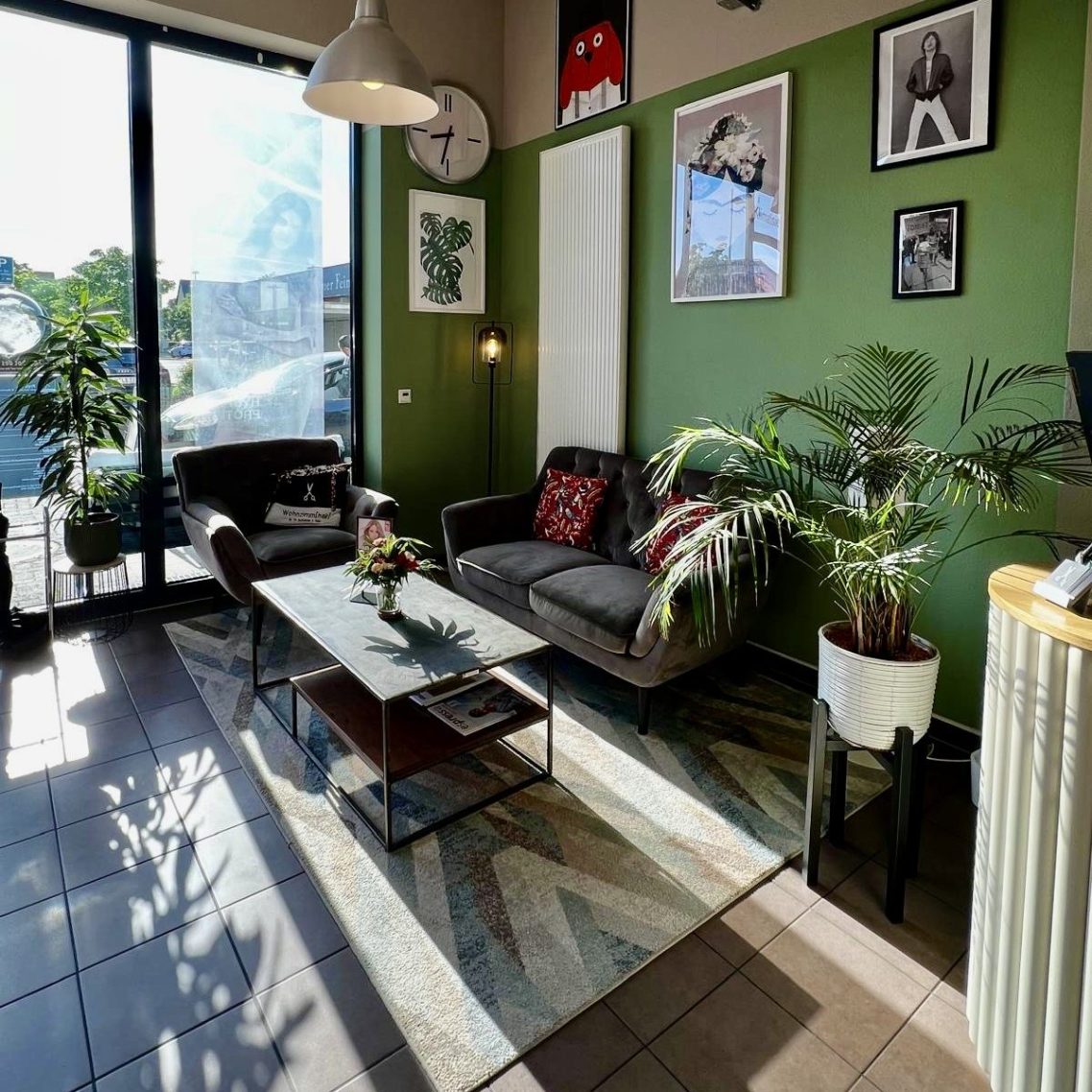 Friseursalon "Wohnzimmer(Hair)" mit beleuchtetem Schild und großen Fenstern.